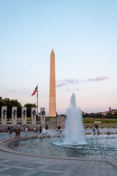 the washington monument and fountain in washington d c, with people walking around it at sunset