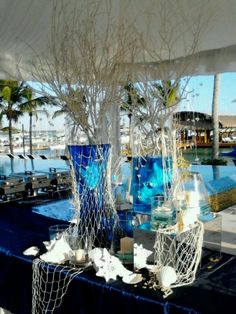 two blue vases with white branches are sitting on a table next to the water