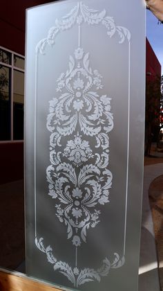 a frosted glass sign with an ornate design on it's side in front of a building