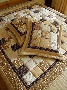 two pillows on top of a bed with brown and white quilts in the middle