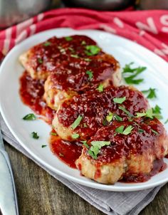 two pieces of meat covered in marinara sauce on a white plate