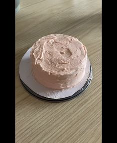 a pink frosted cake sitting on top of a white plate