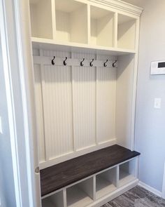 a white mud room with some benches and coat racks