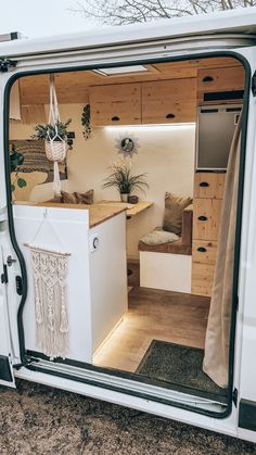 the interior of a camper van with its door open to reveal a kitchen and living area