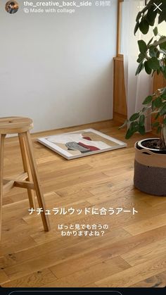 a wooden stool sitting on top of a hard wood floor next to a potted plant