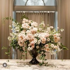 a vase filled with lots of pink and white flowers on top of a marble table