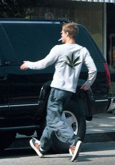 a man walking past a black van on the side of the road with his foot in the air