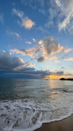 the sun is setting over the ocean with clouds in the sky and waves on the beach