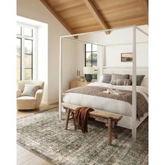 a bedroom with a bed, chair and rug on the floor in front of large windows