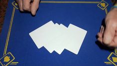 four white cards being held by two hands on a blue cloth with gold trimmings