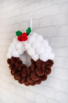 a white and brown wreath hanging on a brick wall next to a red candle holder