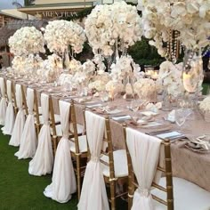 a long table is set with white flowers and place settings for the guests to sit down