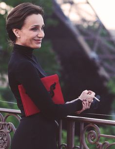 a woman in a black dress holding a red folder