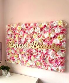 a pink and white flower wall with the word renew beauty written on it in gold lettering