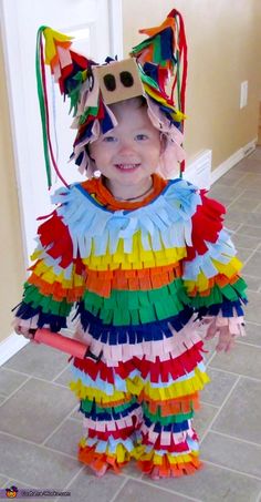 a young child wearing a costume made out of strips of colored paper with a cat mask on it's head