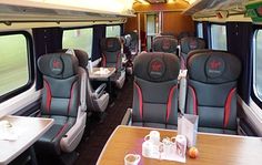 an empty train car with tables and chairs on each side, along with two windows