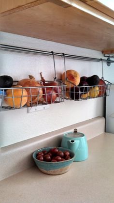 some food is sitting in a wire basket on the counter top next to a bowl of fruit