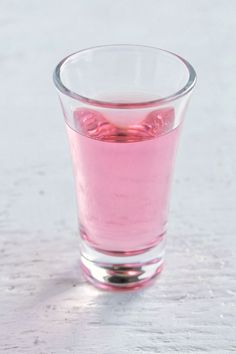 a glass filled with pink liquid sitting on top of a table