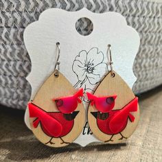 wooden earrings with red cardinals on them and a white flower in the back ground