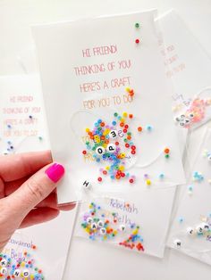 someone is holding up some greeting cards with colorful beads on the bottom and one in the middle