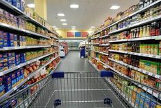 an empty shopping cart in a grocery store filled with lots of food and drink items