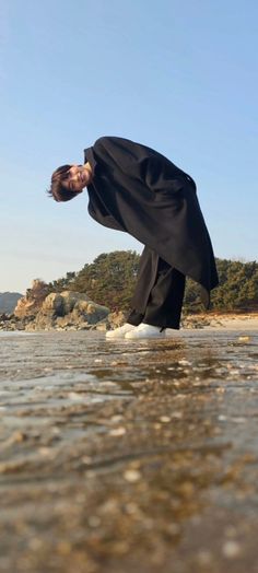 a man in black is standing on his feet in the water