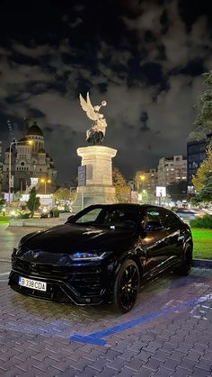 a black car parked in front of a statue