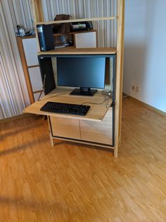 a computer desk with a keyboard and monitor on it in front of a wall mounted shelf