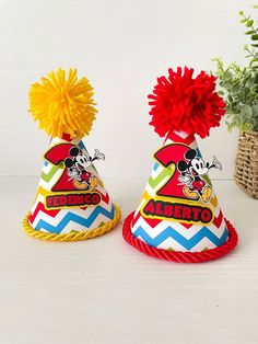 two mickey mouse party hats with pom - poms on top, sitting next to each other