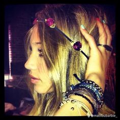 a woman with long blonde hair and bracelets on her head is holding something up to her ear