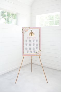 a pink and white wedding seating chart on a easel in a room with wood floors