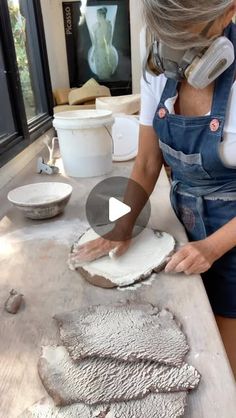 a woman in overalls is making bread on a table