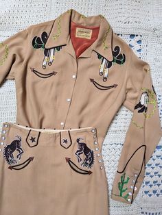 FOR SALE - Rare 1940s 1950s western blouse and skirt suit by Frontex. Size 14 L. Suit features Frontex's iconic bucking bronco, saddles and cacti embroideries in tones of red, green and brown, smiley pockets with arrow leather trims on both piece, opens on each sides of the hips with snaps closure. Pencil skirt, quite long. Made of a warm beige fine wool fabric.  Size medium. Measurements: Blouse: 36" up to 38" max Skirt: Waist: 28" Hips: 38" Length: 32"  Condition: Very good - 2 large but faint Fitted Western Shirt With Button Closure, Vintage Western Short Sleeve, Cowgirl Western Wear, Western Button-up Tops With Pockets, 1950s Western, Vintage Button-up Shirt For Rodeo, Western Snap Button-up Tops, Western Blouse, 2 Piece Skirt