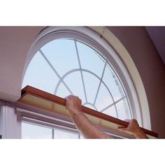 a man is working on a window with the help of a curtain rod in front of him