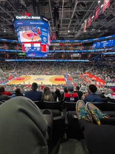 an indoor basketball game is being played in a large arena with people sitting on the seats