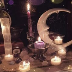 candles are lit in front of a crescent shaped candle holder on a table with other items