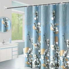 a blue shower curtain with white flowers on it in front of a sink and mirror