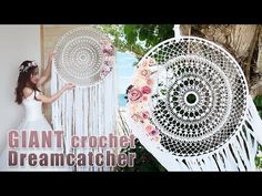 a woman in a white dress is holding a large dream catcher