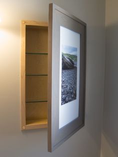 an empty shelf is hanging on the wall next to a framed photograph and some bookshelves