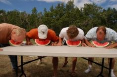 four people are eating watermelon on a table