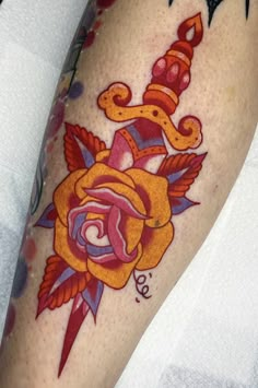 a close up of a person's leg with a tattoo on it and an orange rose