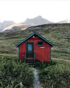 a small red building sitting on top of a lush green hillside