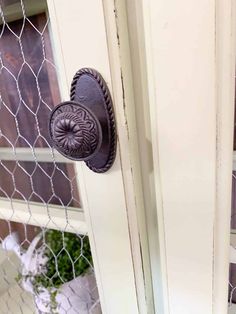 an old door handle on the side of a white house with a chain link fence behind it