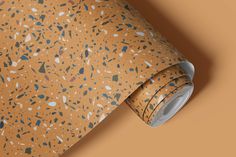 an orange wallpaper with blue and white speckles on it, next to a roll of brown paper