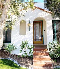 a white house with green shutters on the front door and steps leading up to it