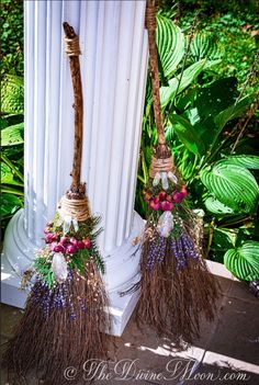 two brooms are decorated with flowers and leaves on the side of a white pole