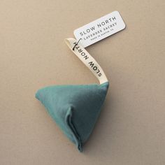 a green pillow with a tag on it sitting next to a small triangle shaped object