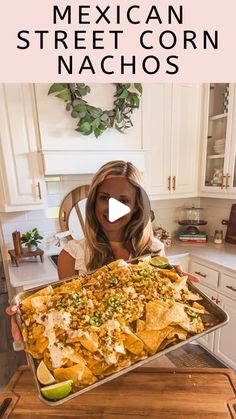 a woman holding a tray full of nachos with the words mexican street corn nachos