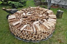 a large pile of wood sitting on top of a lush green field