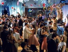 a group of people standing around each other in a room with balloons and streamers